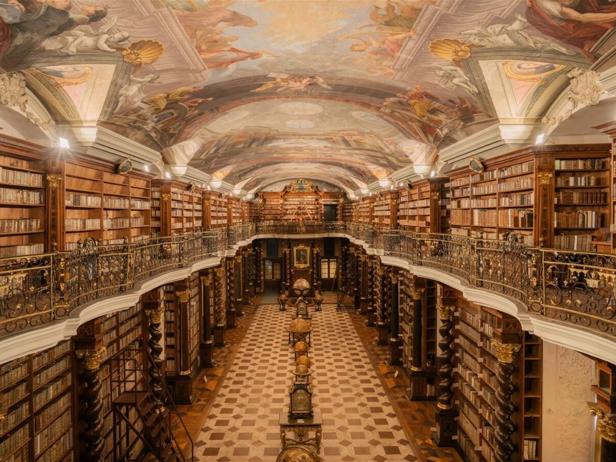 The beautiful library in Klementinum with old books and a painted ceiling.